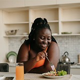 Woman smiling while eating healthy meal at home