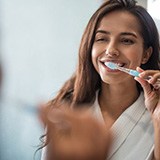 Woman brushing teeth to prevent dental emergencies