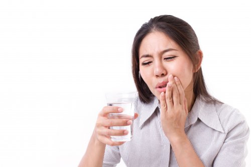 Women in tooth ache holding glass of water