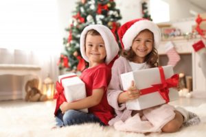 two kids holding christmas gifts