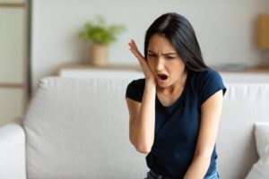 a woman holding her teeth in pain