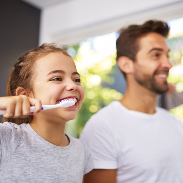 father and daughter brushing their teeth side by side