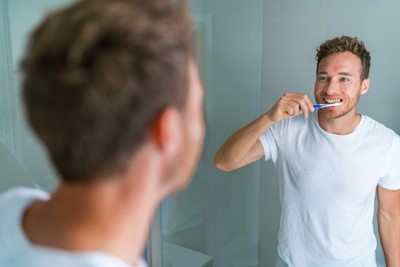 A person brushing his teeth in front of mirror